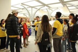 group of students standing listening to a tour guide inside a building