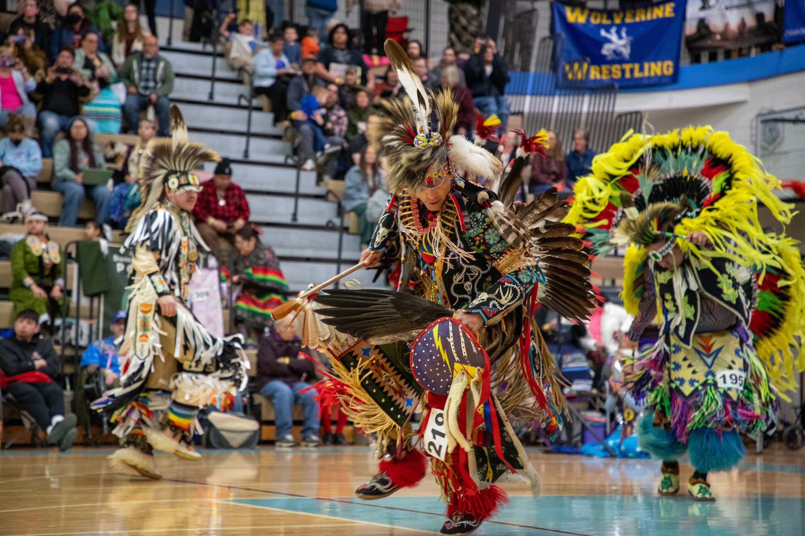 dancers in a gym wearing regalia