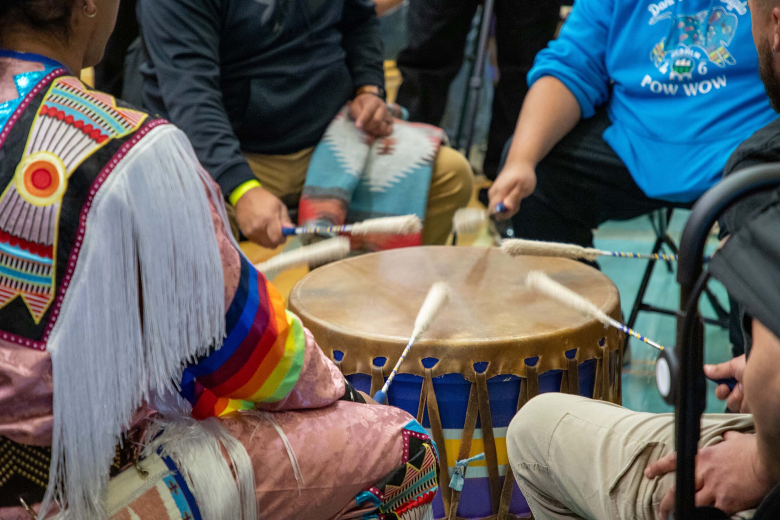 large drum with hands holding mallets around it in a circle
