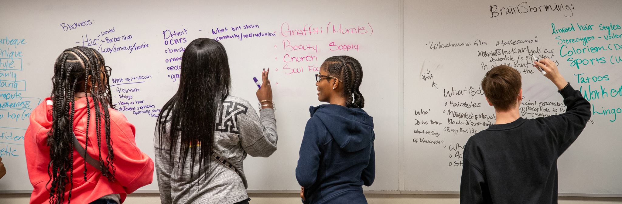 kids with their backs to us writing on a white board