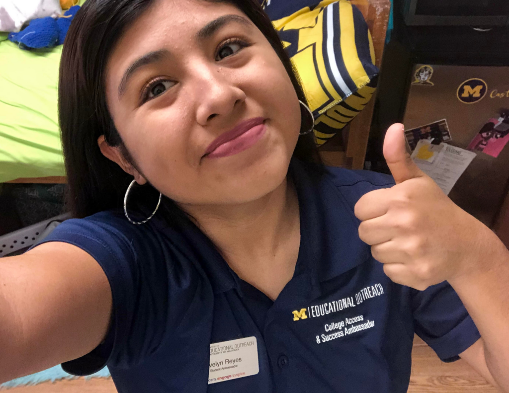 girl with dark hair and dark blue shirt giving a thumbs up