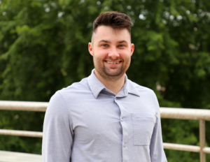 headshot of Alex Shoop in light blue button down shirt outdoors
